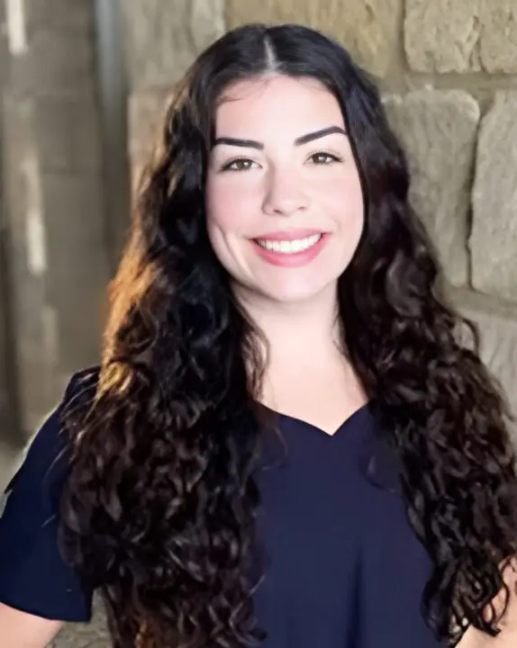 Portrait of a smiling woman with long, curly hair.