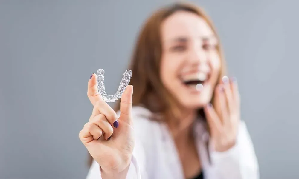 Woman holding clear teeth aligner.