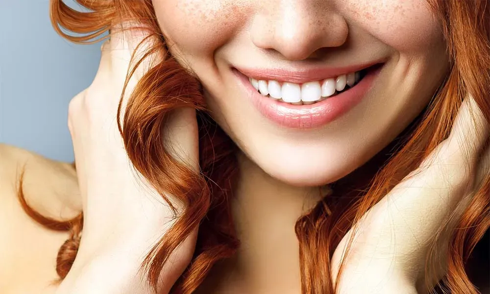 Redhead woman smiling, showing white teeth.