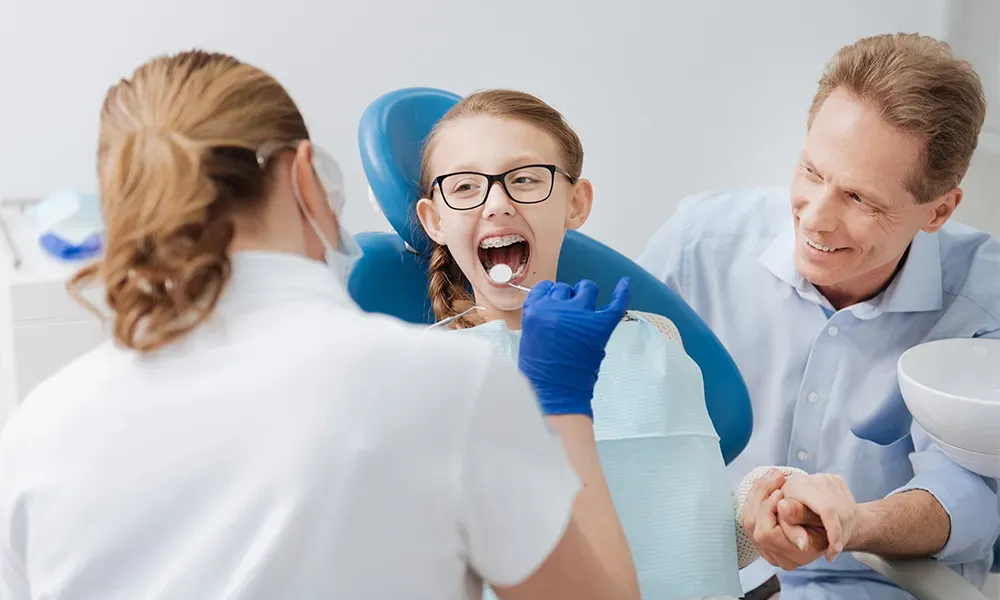 Girl at dentist with father for checkup.