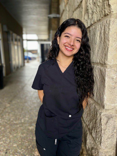 Smiling healthcare worker in black scrubs against wall