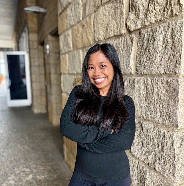 Young smiling woman leaning against stone wall