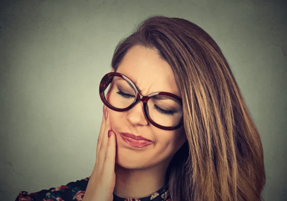 Woman with glasses experiencing toothache.